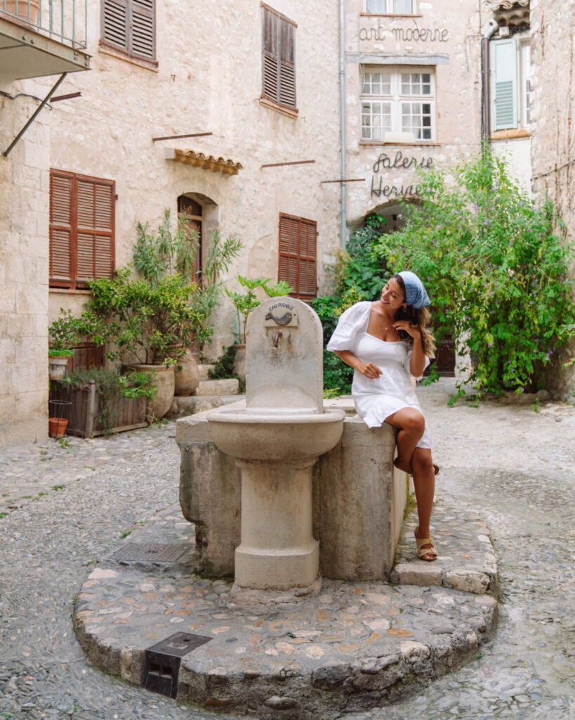 girl sitting on fountain in Saint Paul de Vence, south of france