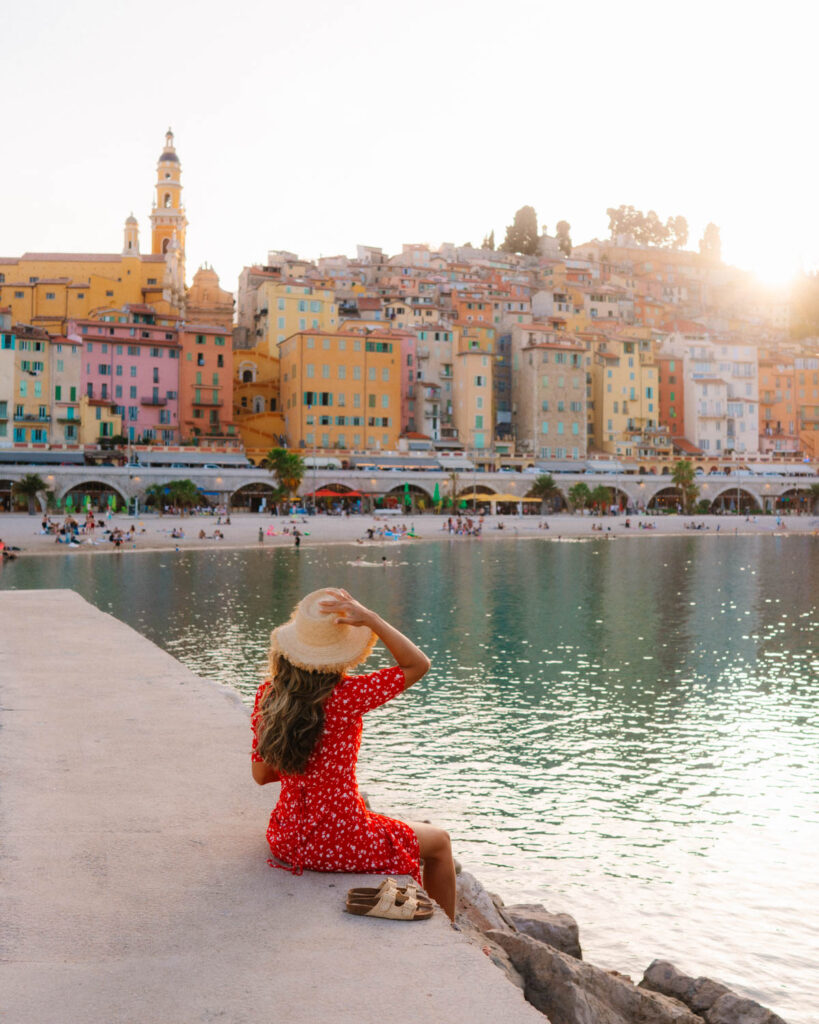 girl watching sunset over beach and colourful village in Menton in the south of france 