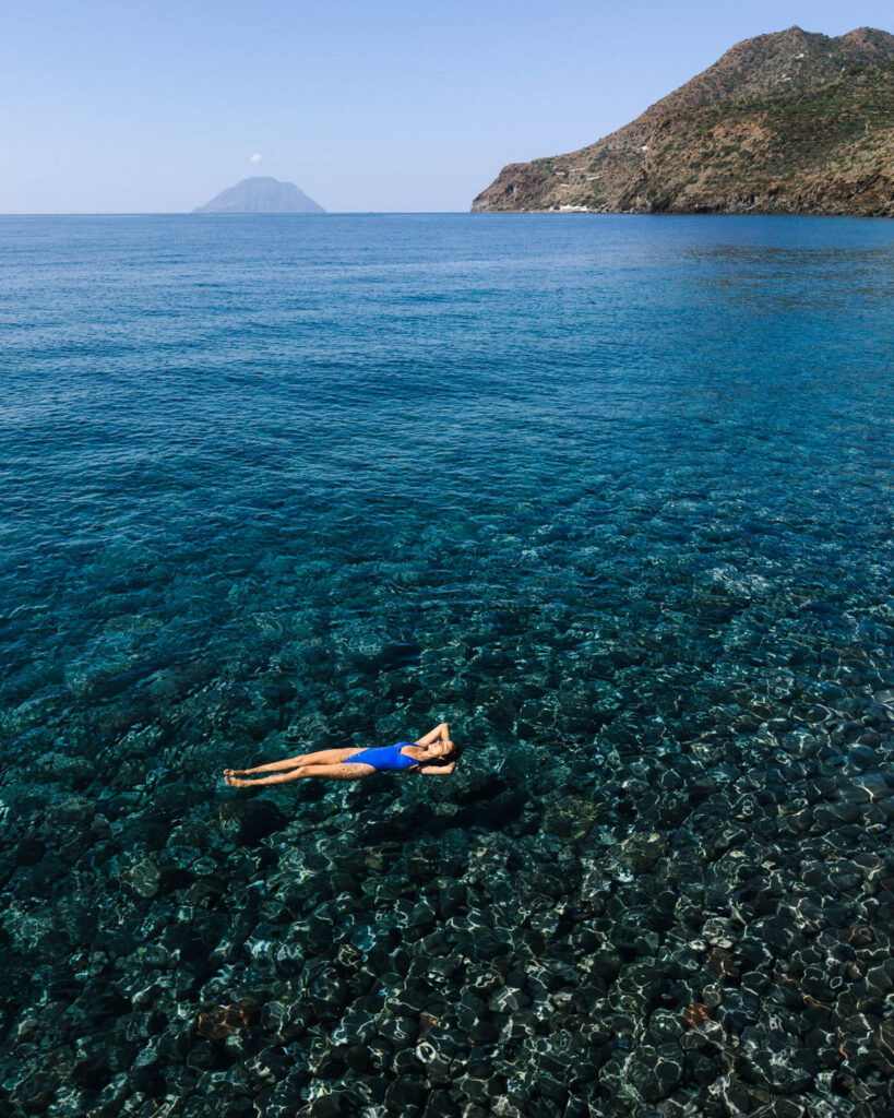 Girl swimming in a beach in Filicudi part of the Aeolian island one of the best places to visit in Sicily