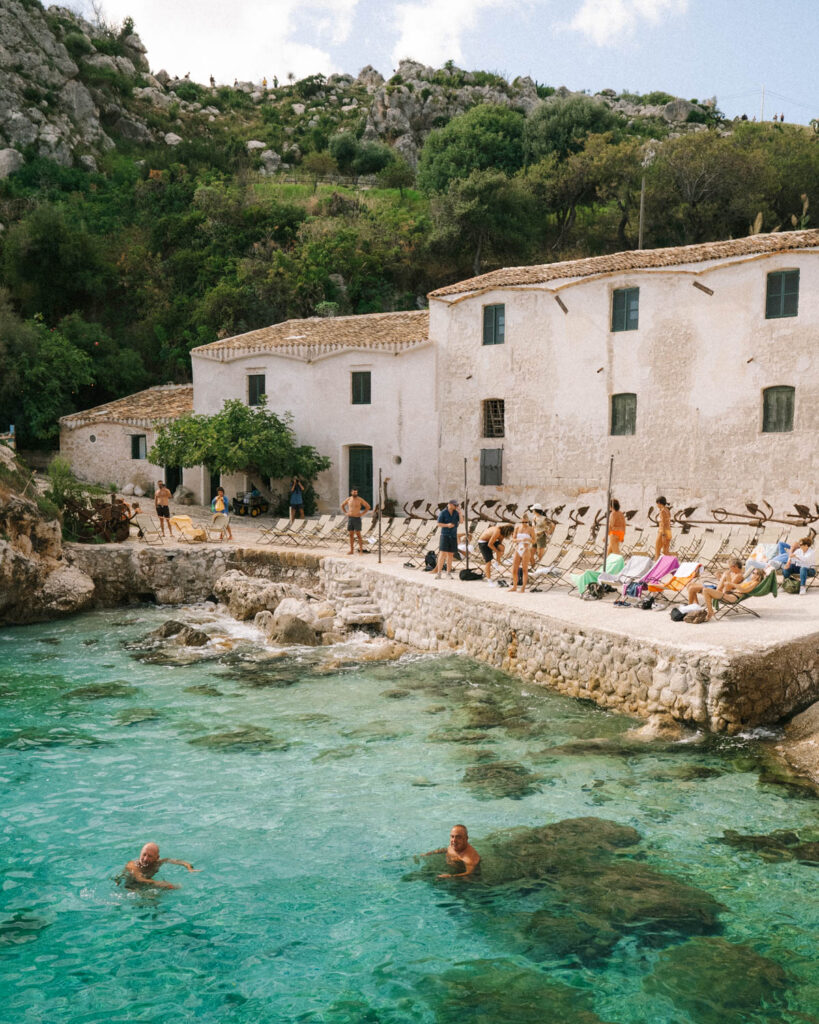 bathers in the crystal blue waters of Tonnara di Scopello beach sicily Italy